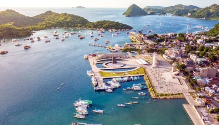 Aerial view of Labuan Bajo harbor with boats, sunset, and Flores Sea in the background. Gateway to Komodo Island tours.