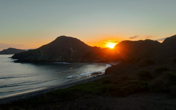 Sunset over Komodo National Park viewed from Bose Komodo boat, golden sky reflecting on calm turquoise sea.