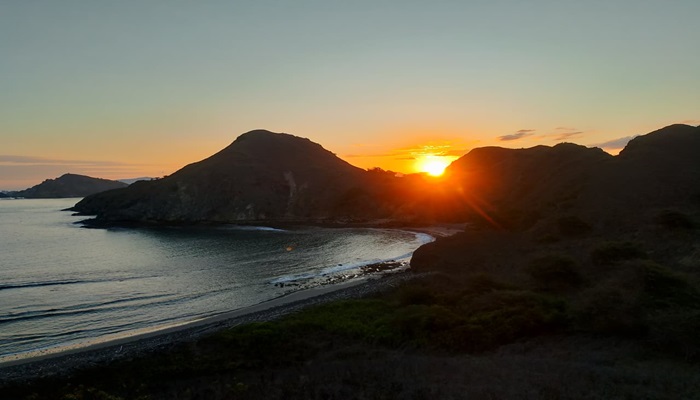 Sunset over Komodo National Park viewed from Bose Komodo boat, golden sky reflecting on calm turquoise sea.