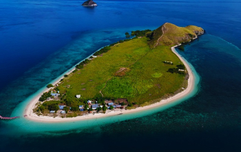 Aerial view of Kenawa Island’s green hills and white beach between Sumbawa and Lombok, a hidden stop on Komodo tour packages from Bali or Lombok.