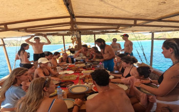 Local Komodo guide leading tourists through Rinca Island savanna with Komodo dragon in the distance under golden tropical sun.