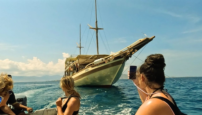 Luxury Phinisi boat sailing past Padar Island at sunrise during a Komodo boat tour 3 days 2 nights.